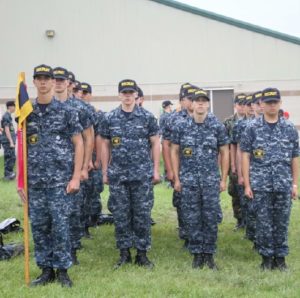 Mark Suminski, far left holds the guidon during role call at Sea Cadets on June 10, 2015. The flag’s colors represent the division Suminski is in.