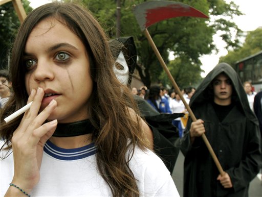 Paraguayan student Paulina Velazquez, left, of the Adventist School , pretends to smoke during a No-Tabacco march on World No Tobacco Day in downtown Asuncion, Paraguay, Wednesday, May 31, 2006. The World Health Organization said smoking is the single biggest preventable cause of death worldwide, claiming 4.9 million lives a year. (AP Photo/Jorge Saenz)