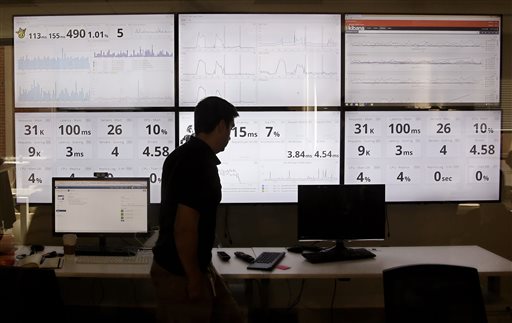 An employee in the software development department of DraftKings, a daily fantasy sports company, walks past screens displaying the companys online system stats in Boston.  Customers of the two biggest daily fantasy sports websites have filed at least four lawsuits against the sites in Oct. 2015, following cheating allegations and a probe into the largely-unregulated multi-billion dollar industry. In court papers, the customers accused the DraftKings and FanDuel sites of cheating, and argued they never would have played had they known employees with insider knowledge were playing on rival sites.  (AP Photo/Stephan Savoia)