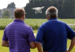 A DJI Phantom 3 drone is flown by Matthew Creger, left, marketing director for Intelligent UAS, as he talks with Chip Bowling, from Newburg, Md., president of the National Corn Growers, during a drone demonstration at a farm and winery, on potential use for board members of the National Corn Growers, Thursday, June 11, 2015 in Cordova, Md. (AP Photo/Alex Brandon) 
