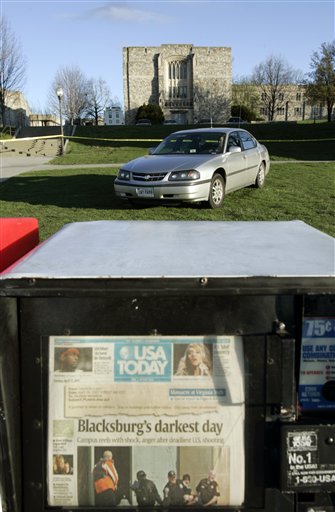 A newspaper vending machine shows a headline of Mondays shooting as a security guard sits in his car outside Norris Hall on the campus of Virginia Tech University in Blacksburg, Va., Tuesday, April 17, 2007. A gunman killed some 30 students and others in the hall during a rampage on Monday that left a total of 33 dead. (AP Photo/Steve Helber)
