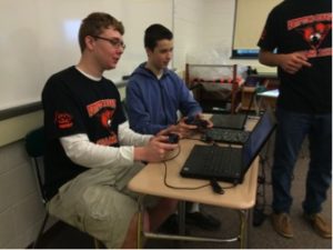 3)Team member Henry Will (left) helps Max Potter (right) on controlling the robot on April 29, 2016. They use game controllers along with programmed computers to know which buttons to press and when. (Broadcaster/Jenny Kim)