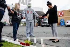 Francine Prieto-Estrada, left, leads Donald Pride and Elisa Castro in a prayer at memorial site for the gunned-down 12-year-old at Circle K gas station on Highland Avenue and Orange Street in San Bernardino, Calif., on Monday, March 14, 2016. The 12-year-old was shot and killed late Sunday, and a 14-year-old was wounded in the same shooting. (Rachel Luna/San Bernardino Sun via AP) 