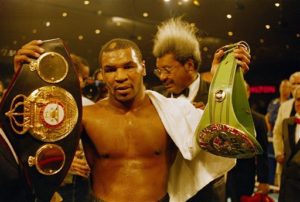 Mike Tyson holds up two of the three heavyweight championship belts after defeating Tony Tucker on Aug. 1, 1987 in Las Vegas, in the undisputed heavyweight championship fight. Tyson defeated Tucker in the 12-round fight by a unanimous decision.  Manager Don King is in background. (AP Photo/Jeff Robbins)