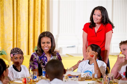 First lady Michelle Obama, accompanied by Let’s Move! Executive Director Deb Eschmeyer, right, talks with children in the East Room at the White House in Washington, Wednesday, June 3, 2015, after they helped prepare and eat food harvested from the White House Kitchen Garden with children from all over the country who participated in events with the "Let’s Move!" campaign. The "Let's Move!" campaign, started by Michelle Obama seeks to combat the epidemic of childhood obesity and encourage a healthy lifestyle. (AP Photo/Andrew Harnik)