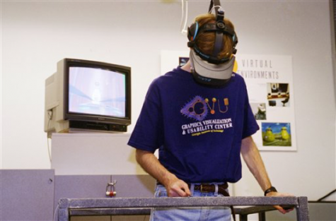 Drew Kessier, a doctorate student at Georgia Tech, demonstrates a computer generated virtual reality headset used in treating acrophobia, the fear of heights in Atlanta on Monday, March 27, 1995. Patients stand on a platform with a railing to hold onto as images that simulate them rising and falling are displayed on their headsets and on the monitor behind them. (AP Photo/Tannen Maury)