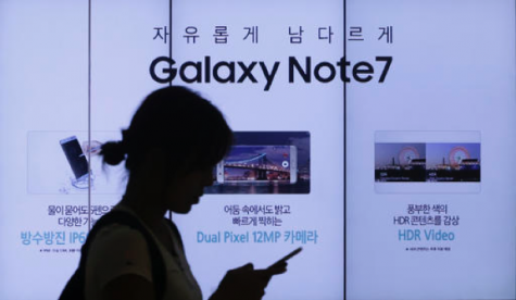 In this Friday, Sept. 2, 2016, file photo, a woman walks by an advertisement of the Samsung Electronics Galaxy Note 7 smartphone at the company's showroom in Seoul, South Korea. The Federal Aviation Administration said Thursday night, Sept. 8, 2016, that because of recent fire reports involving the Galaxy Note 7 smartphone, passengers shouldn’t use or charge one or stow one in checked baggage. The three biggest U.S. airlines: American, Delta and United, said Friday that they were studying the FAA warning but it was unclear how they would make sure that passengers keep the Samsung devices powered off. (AP Photo/Ahn Young-joon, File)