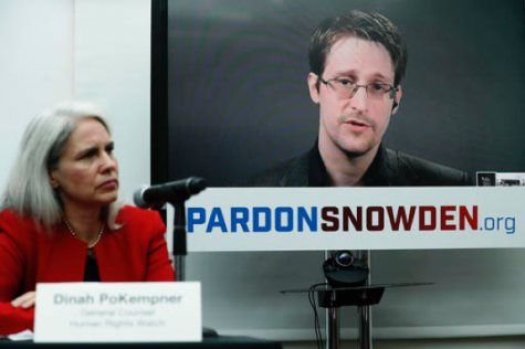 Dinah PoKempner, left, general council for Human Rights Watch, listens as Edward Snowden speaks on a television screen via video link from Moscow during a news conference to call upon President Barack Obama to pardon Snowden before he leaves office, Wednesday, Sept. 14, 2016, in New York. Human and civil rights organizations, including the ACLU, Human Rights Watch and Amnesty International, launched a public campaign to persuade Obama to pardon the former National Security Agency contractor, who leaked classified details in 2013 of the U.S. government's warrantless surveillance program before fleeing to Russia. (AP Photo/Mary Altaffer)