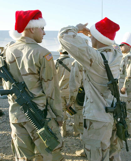 U.S. Army soldiers wear Santa Claus hats during a Christmas event at Camp Pennsylvania  in the Kuwaiti desert Wednesday, Dec. 25, 2002. (AP Photo/Anja Niedringhaus)