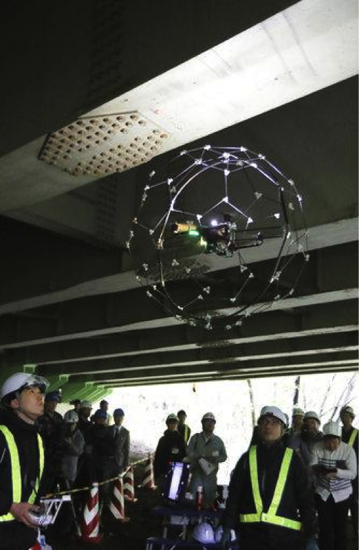 A drone lights up and takes photos while flying in a dark and narrow space under a bridge at Sendai City, Miyagi prefecture on May 16, 2017. Kazunori Ohno, Japanese Assistant Professor of Tohoku University and his team developed a drone which doesnt fall even colliding with something like bridge. Drone is guarded with football-shape device (96cm diameter, 2.6kg), made of strong and special material, can fly stable even it bumping into a building or other things. ( The Yomiuri Shimbun via AP Images )

