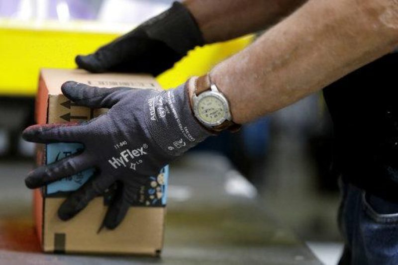 In this file photo from Tuesday, Aug. 1, 2017, an employee packages a product at the Amazon Fulfillment center in Robbinsville Township, N.J.. On Wednesday, Oct. 25, 2017, Amazon said that it will launch a new service in November that will let delivery people inside homes to drop off packages. (AP Photo/Julio Cortez)
