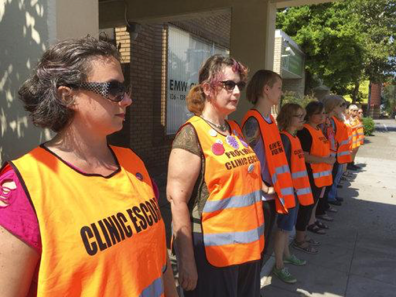 In this Monday, July 17, 2017 photo, Meg Stern, left, and other escort volunteers lined up outside the EMW Womens Surgical Center in Louisville, Ky. The clinic’s fate will be decided after a 60 day brief from both sides. (AP Photo/Dylan Lovan)
