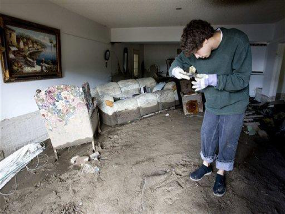 Unable to stand upright due to large amounts soil covering the floor, Brian Laguna recovers personal belongings after a mudslide caused by heavy rains damaged his house in La Canada Flintridge, Calif. on Monday, Feb. 8, 2010. Another storm is expected to hit the Los Angeles area Tuesday. (AP Photo/Hector Mata)