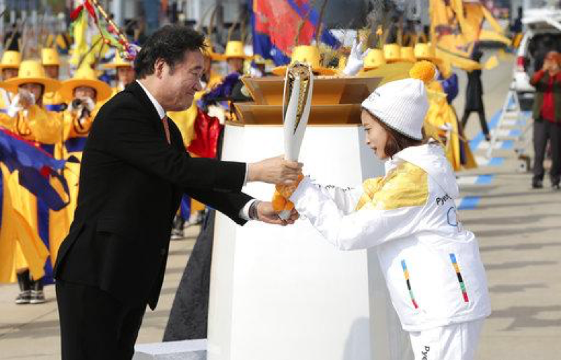 South Korean Prime Minister Lee Nak-yon, left, passes an Olympic torch to torch bearer, South Korean figure skater You Young, at Incheon Bridge in Incheon, South Korea, Wednesday, Nov. 1, 2017. The Olympic flame arrived in South Korea on Wednesday where it will be passed throughout the country by thousands of torchbearers on a 100-day journey to the opening ceremony of the 2018 Winter Olympics in Pyeongchang. (AP Photo/Lee Jin-man)
