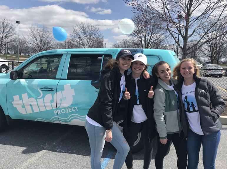 From left to right, sophomores, Leah Koppenhaver, Katherine Clark, Claire Sheppard, and Olivia Bratton, stand in front of the Thirst Project car. The Thirst Project has raised money to build 1,754 wells in 13 countries to save a total of 285,599 lives. (Broadcaster/Clare Canavan) 
