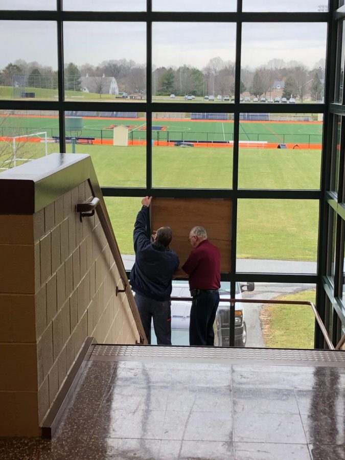 Custodians tape wood to secure the broken window on Monday, January 13, 2019. The stairway in the F wing was closed off to keep students safe. (Broadcaster/Eva Baker)