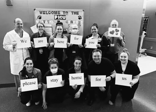 Dr. Brian Clark (top left) holds up a sign with other medical workers at the Penn State Health Medical Center. Dr. Clark is a Pediatric Cardiac Surgeon. (Submitted by Kate Clark)