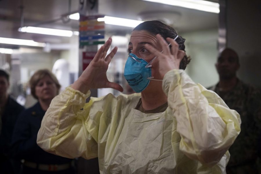 Lt. Cmdr. Nevin Yazici demonstrates how to properly fit an N95 respiratory protective device aboard the hospital ship USNS Comfort in New York harbor on March 31, 2020.  The N95 mask or any mask must fit tightly against the face to offer protection.  (U.S. Navy/Mass Communication Specialist 2nd Class Sara Eshleman/CC BY 2.0)