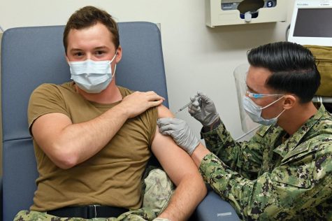 Hospital Corpsman 3rd Class David Tuil, assigned to the Preventive Medicine Department at Naval Health Clinic Hawaii (NHCH), administers one of the first Pfizer-BioNTech COVID-19 vaccines at NHCH to Hospital Corpsman 3rd Class Gage Finn, a member of the COVID-19 Expeditionary Testing Team at NHCH, Dec. 16, 2020.  Pfizer has earned approval from the FDA for its vaccine for 12-15 year olds.  (U.S. Navy photo by Macy Hinds/CC BY 2.0)