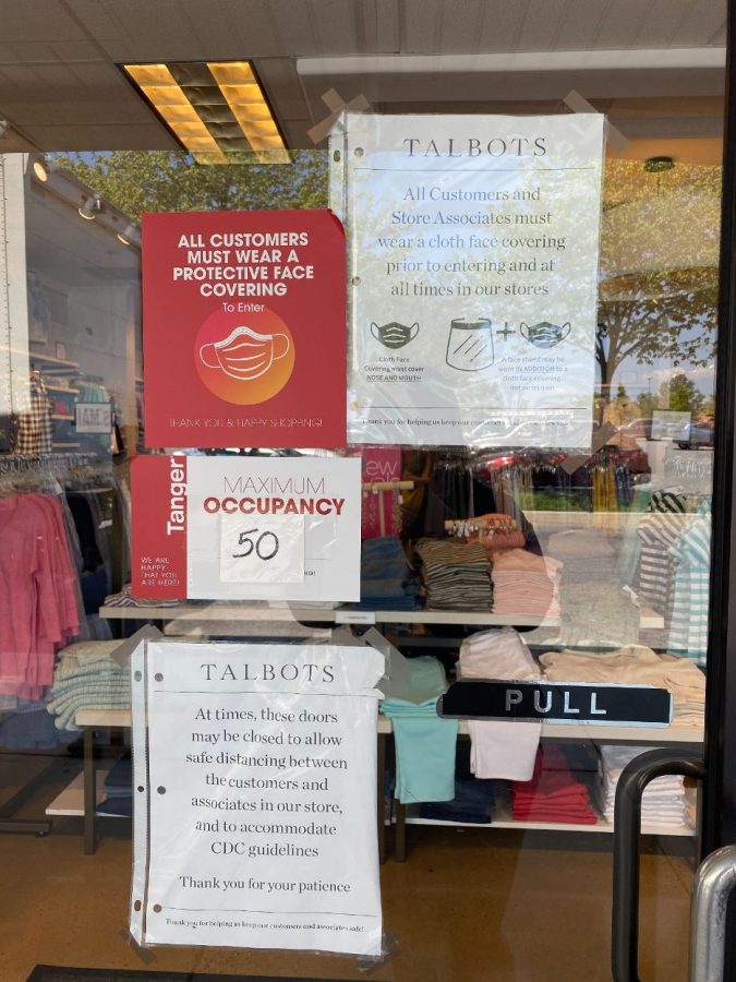 Stores notify shoppers that mask and occupancy guidelines are being followed. Occupancy and mask protocol had been frequently posted on the signs of storefronts at the outlets. (Broadcaster/Keela Delves)