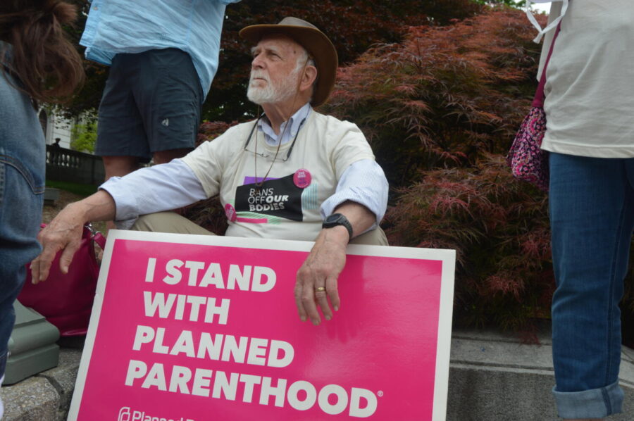 A man sits with an “I stand with Planned Parenthood” sign in his hand. PA Governor Tom Wolf spoke to the crowd and offered his continued support of abortion rights and a womans right to choose. (Broadcaster/Mia Caldonetti) 