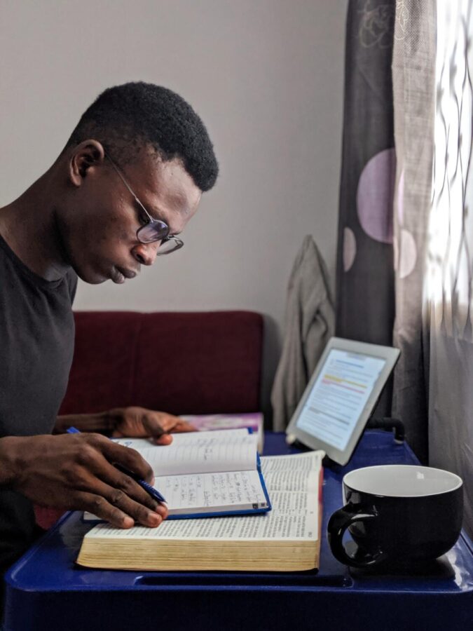 A young man studies with some books and an iPad.  Having a good study space is just one of the many ways to ace your test preparation.  (Oladimeji Ajegbile/Pexels)