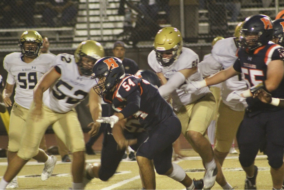 Aiden Edleman (54) runs down the field as McDevitt players circle him. The offensive lineman attempted to protect the quarterback.
