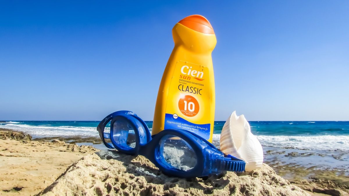 Sunscreen, goggles, and a shell are pictured at the beach.  Applying sunscreen regularly can help protect your skin against sunburn.  (Dimitris Vetsikas from Pixabay/CC0)
